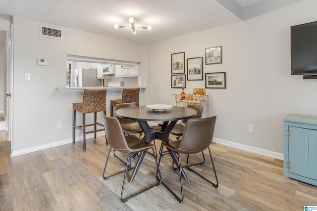 dining area featuring visible vents, light wood-type flooring, and baseboards