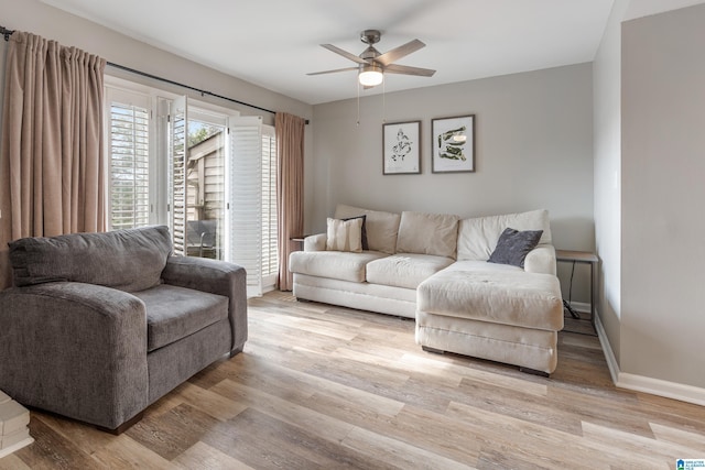 living area featuring light wood-style flooring, a ceiling fan, and baseboards