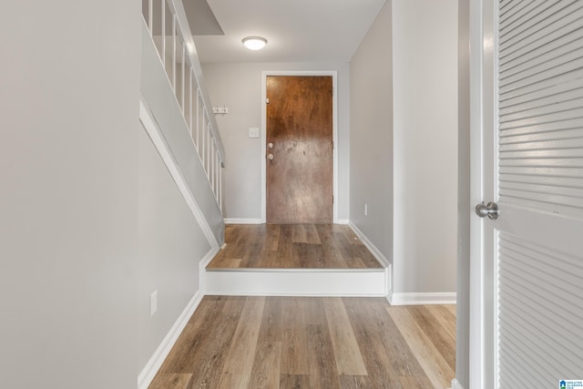 foyer entrance featuring baseboards, wood finished floors, and stairs