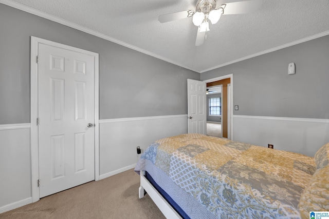 carpeted bedroom featuring ornamental molding, a ceiling fan, and a textured ceiling