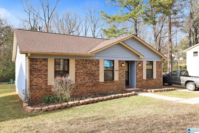 ranch-style home with brick siding, a front lawn, and roof with shingles