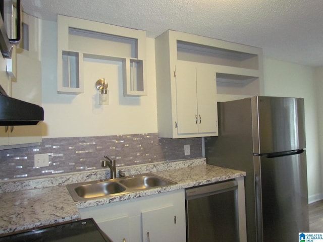 kitchen featuring tasteful backsplash, appliances with stainless steel finishes, white cabinets, a textured ceiling, and a sink