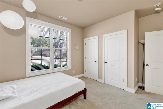 bedroom with light carpet, visible vents, and baseboards