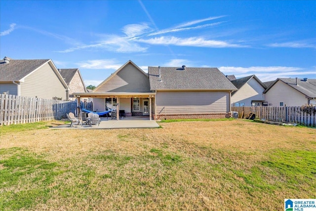 rear view of house featuring a yard, a fenced backyard, and a patio area