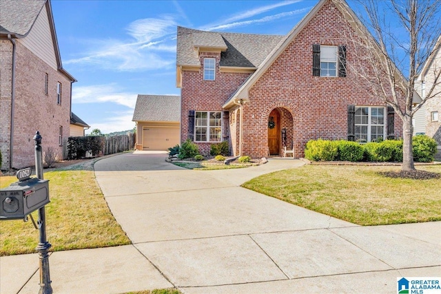 view of front of home with brick siding, concrete driveway, a front lawn, and fence