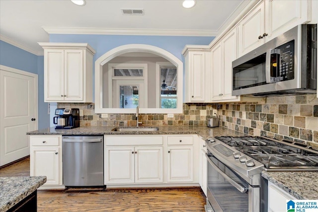 kitchen with visible vents, a sink, tasteful backsplash, stainless steel appliances, and crown molding