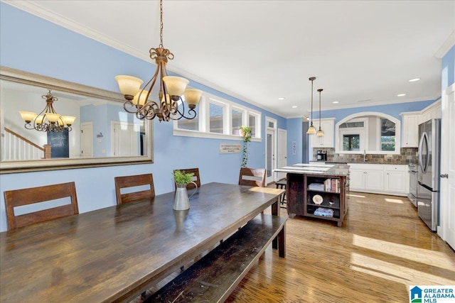 dining space featuring an inviting chandelier, recessed lighting, light wood-style floors, and ornamental molding