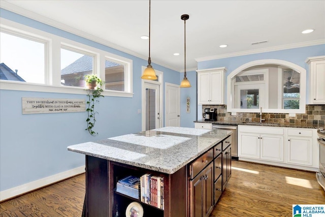 kitchen featuring ornamental molding, a sink, wood finished floors, stainless steel appliances, and decorative backsplash