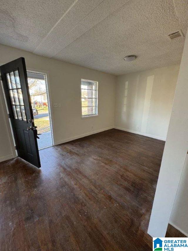 entrance foyer with visible vents, a textured ceiling, baseboards, and dark wood-style flooring