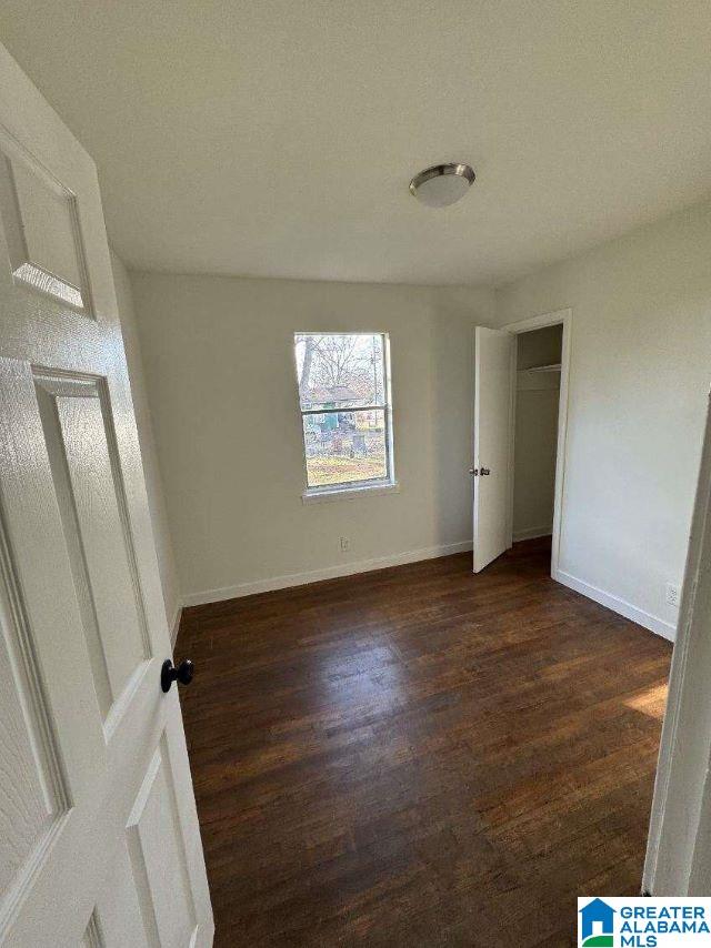 unfurnished bedroom with dark wood-style floors and baseboards