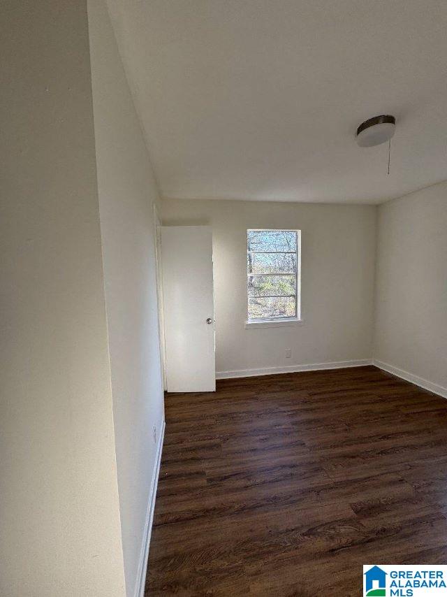 empty room with baseboards and dark wood-style flooring