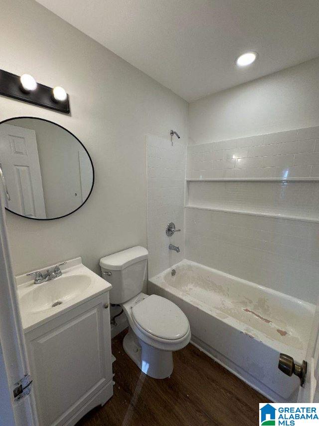 bathroom with wood finished floors, toilet, vanity, and washtub / shower combination