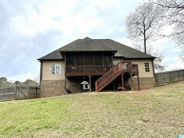 rear view of property featuring a sunroom, stairs, a fenced backyard, a shingled roof, and a lawn