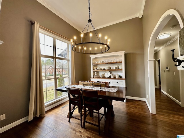 dining space featuring dark wood-style floors, baseboards, ornamental molding, and an inviting chandelier