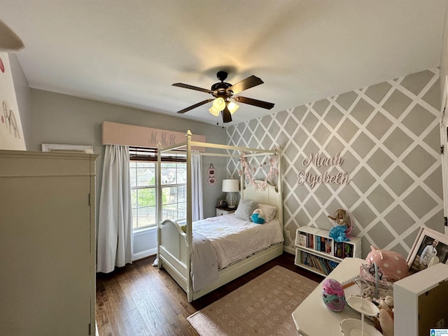 bedroom featuring baseboards, an accent wall, wallpapered walls, dark wood-style floors, and ceiling fan