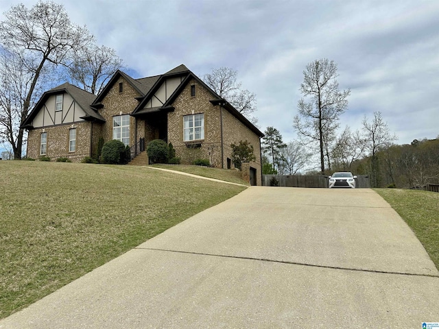 tudor house with a front lawn, brick siding, and concrete driveway