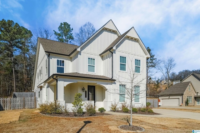 modern farmhouse with a porch, fence, board and batten siding, and an outbuilding