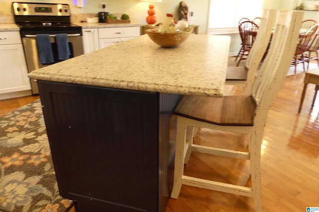 1310 County Road 264, Wedowee, AL 36278 - kitchen with light wood finished floors, a center island, light stone counters, electric range, and white cabinetry