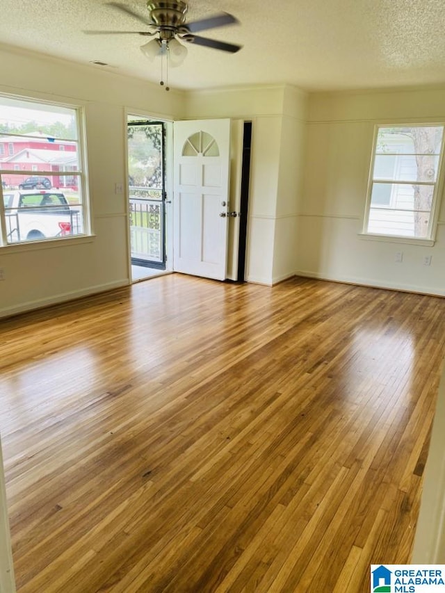 interior space with a ceiling fan, baseboards, wood-type flooring, and a textured ceiling