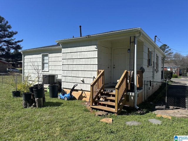 back of property with a lawn, central AC unit, and fence