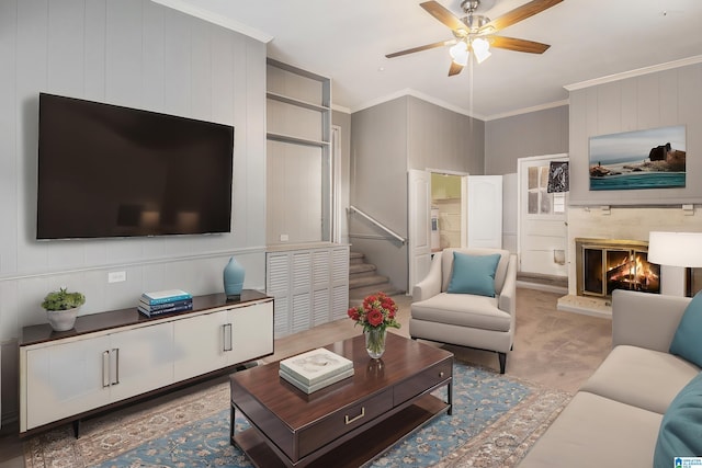 living area with stairway, ceiling fan, a glass covered fireplace, crown molding, and light colored carpet