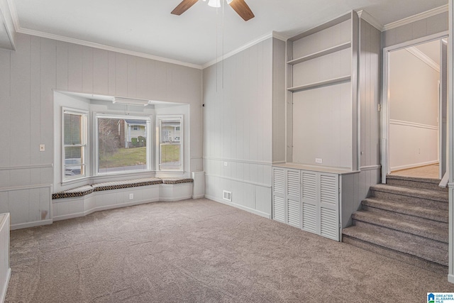 spare room with carpet flooring, stairway, a ceiling fan, and ornamental molding