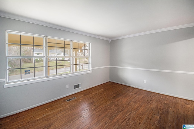 empty room with visible vents, crown molding, baseboards, and wood finished floors