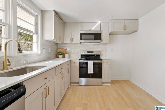 264 Mccalla Rd, Birmingham, AL 35022 - kitchen featuring light wood-type flooring, a sink, tasteful backsplash, appliances with stainless steel finishes, and baseboards