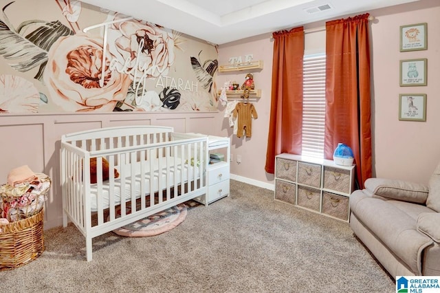carpeted bedroom featuring visible vents, a crib, a wainscoted wall, and a decorative wall