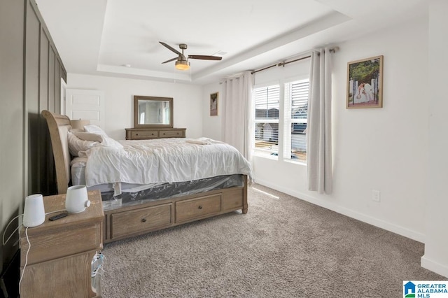 carpeted bedroom featuring a tray ceiling, visible vents, baseboards, and ceiling fan