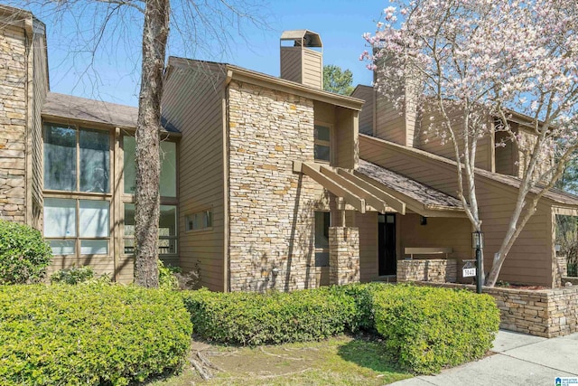 exterior space featuring stone siding and a chimney