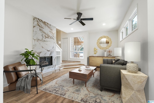 living room featuring ceiling fan, a high end fireplace, wood finished floors, and recessed lighting