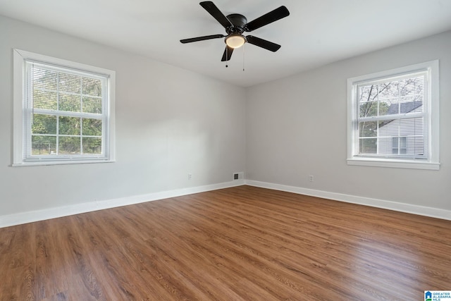 unfurnished room featuring wood finished floors, a healthy amount of sunlight, and baseboards