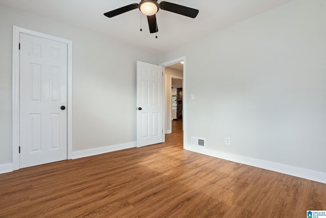 unfurnished bedroom featuring a ceiling fan, wood finished floors, visible vents, and baseboards