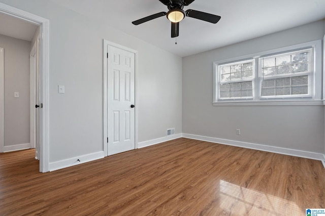 unfurnished bedroom featuring a closet, visible vents, baseboards, and wood finished floors