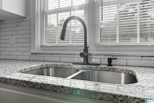 room details featuring decorative backsplash, light stone counters, and a sink