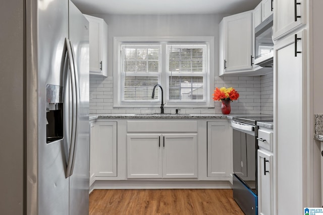 kitchen featuring light wood-style flooring, a sink, backsplash, white cabinetry, and stainless steel appliances