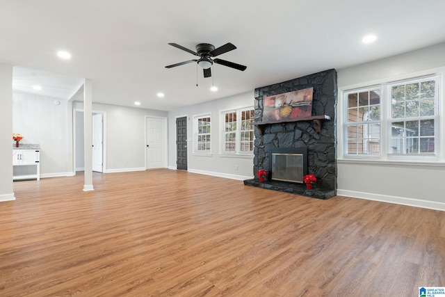 unfurnished living room with light wood-style flooring, plenty of natural light, a ceiling fan, and baseboards