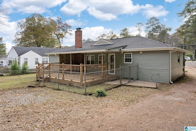 rear view of house with a wooden deck, a shingled roof, a chimney, and fence