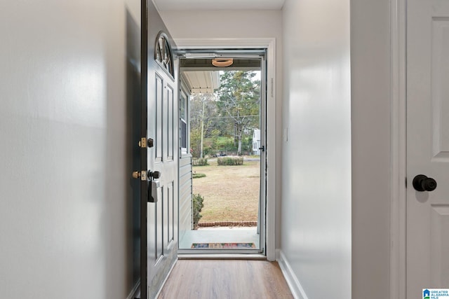 doorway with wood finished floors and baseboards