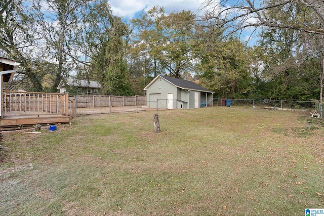 view of yard with a detached garage, an outbuilding, a fenced backyard, and a deck