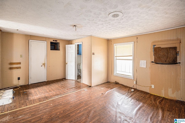 unfurnished room with wood-type flooring, a textured ceiling, and ornamental molding