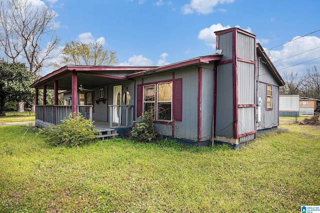 back of property with covered porch and a yard