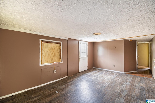 unfurnished room with a textured ceiling, baseboards, and wood finished floors