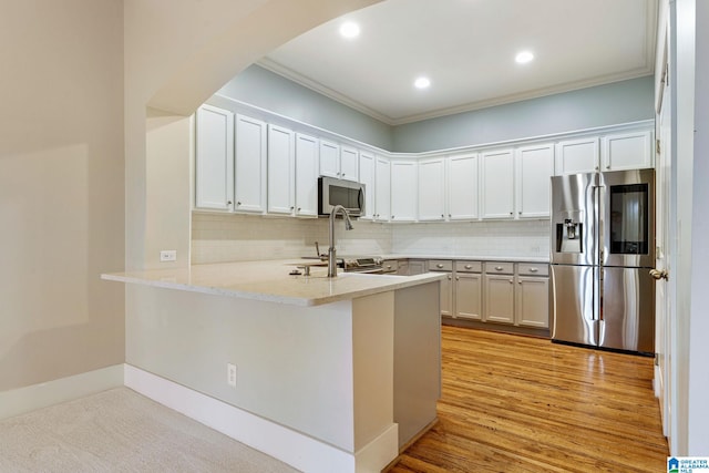 kitchen with a peninsula, arched walkways, backsplash, and stainless steel appliances