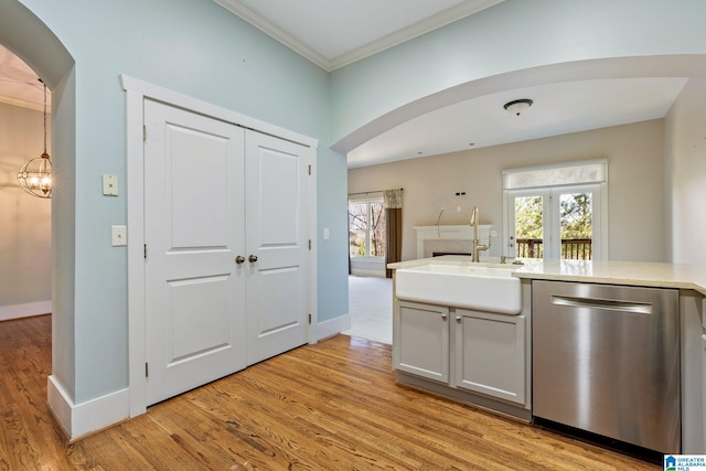 kitchen with a sink, arched walkways, dishwasher, and crown molding