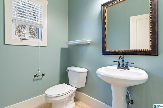 half bath featuring a sink, baseboards, toilet, and tile patterned flooring