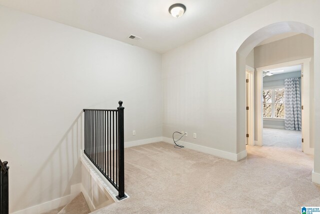 spare room with baseboards, arched walkways, carpet, and visible vents