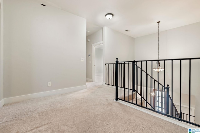 hallway featuring visible vents, an upstairs landing, carpet floors, baseboards, and a chandelier