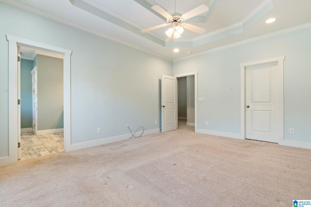 unfurnished bedroom with a tray ceiling, recessed lighting, carpet floors, crown molding, and baseboards